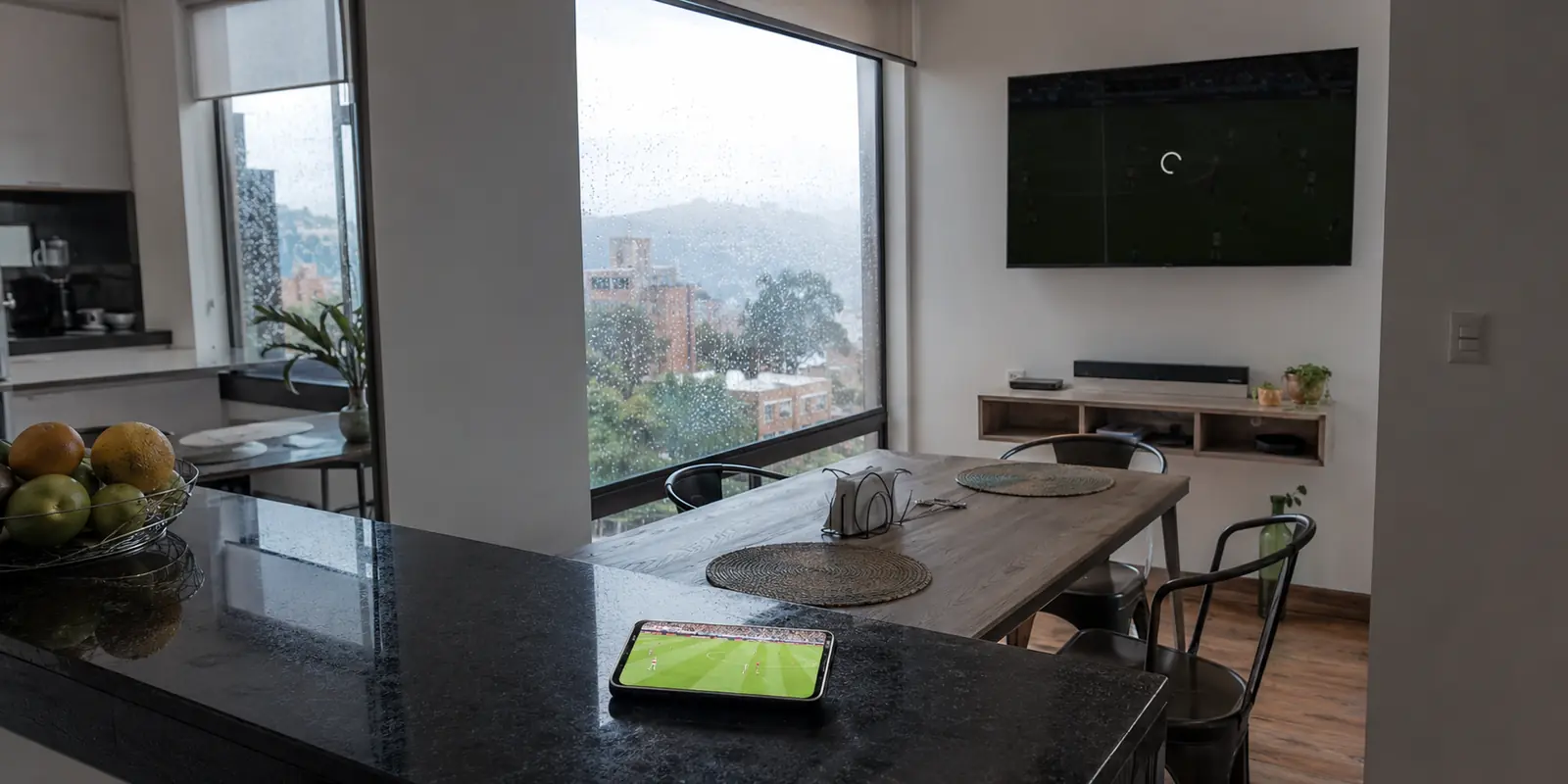 Un teléfono reproduce un partido mientras el televisor del comedor queda detenido en la carga durante una tarde lluviosa en Bogotá