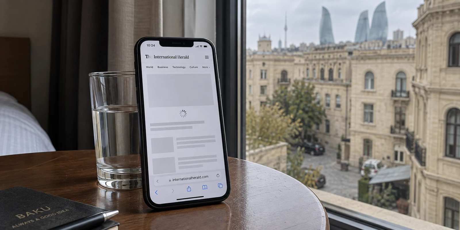 A news page remains loading on a phone in a Baku hotel room.