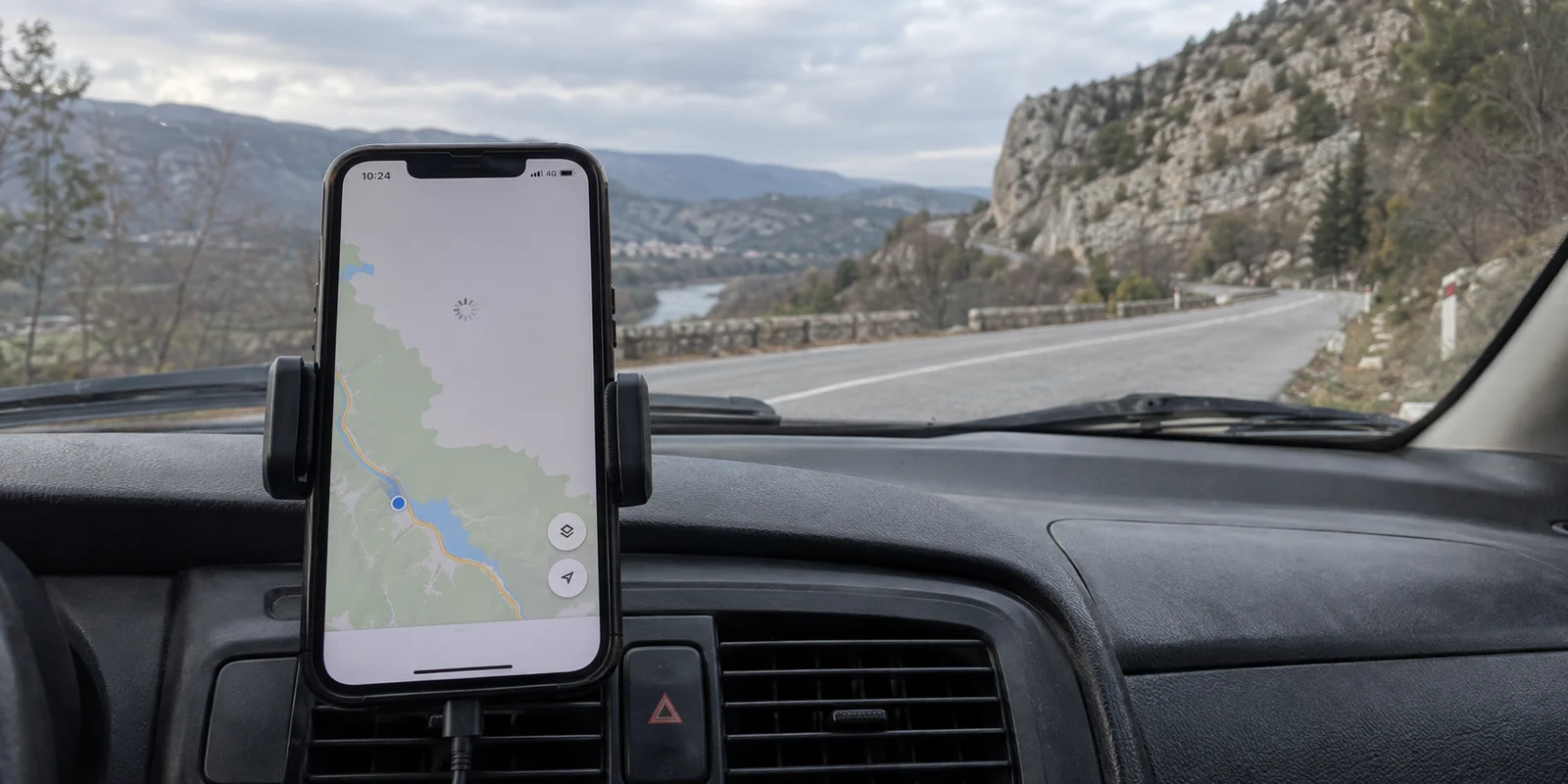 A navigation map stalls on a dashboard phone along a Bosnian road.