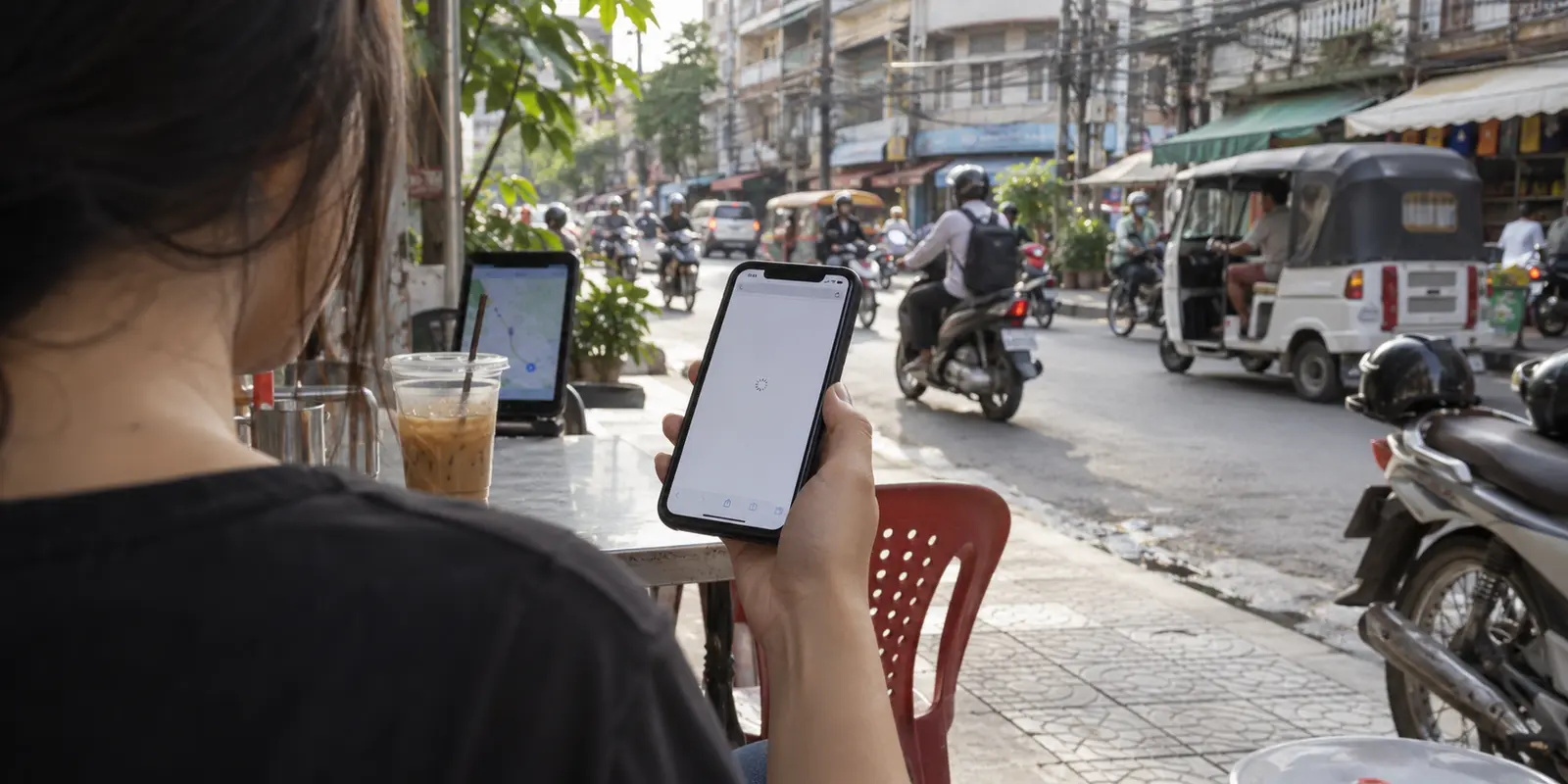 An overseas page keeps loading on a phone beside a busy Phnom Penh street