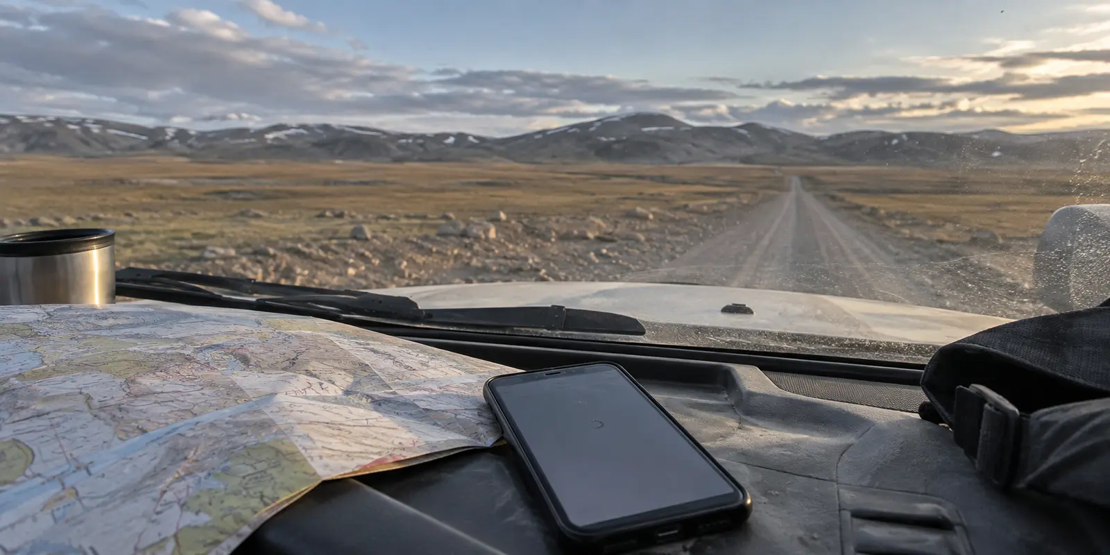 A phone with a stalled connection on the dashboard of an overland vehicle crossing the Mongolian steppe