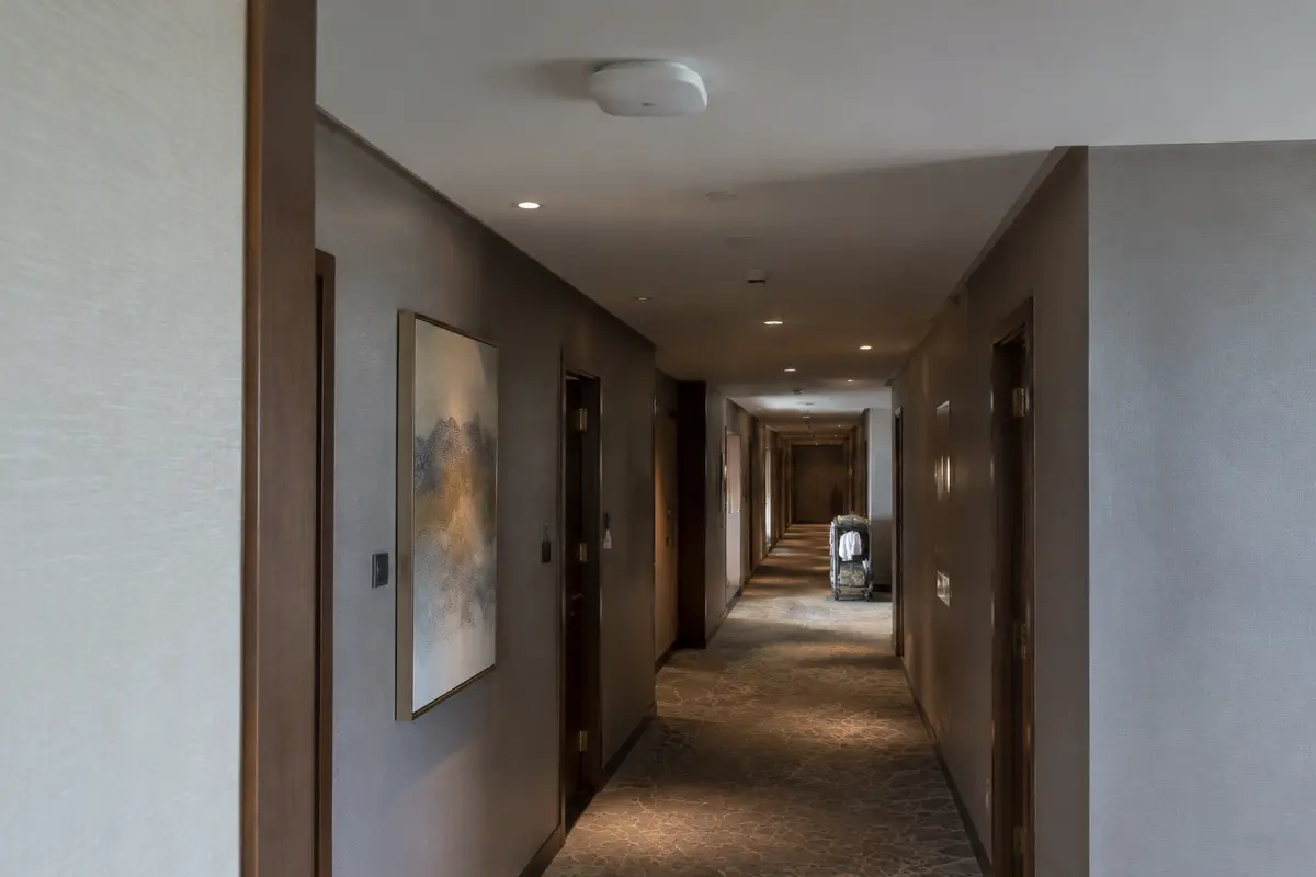 A ceiling-mounted Wi-Fi access point above a long hotel corridor