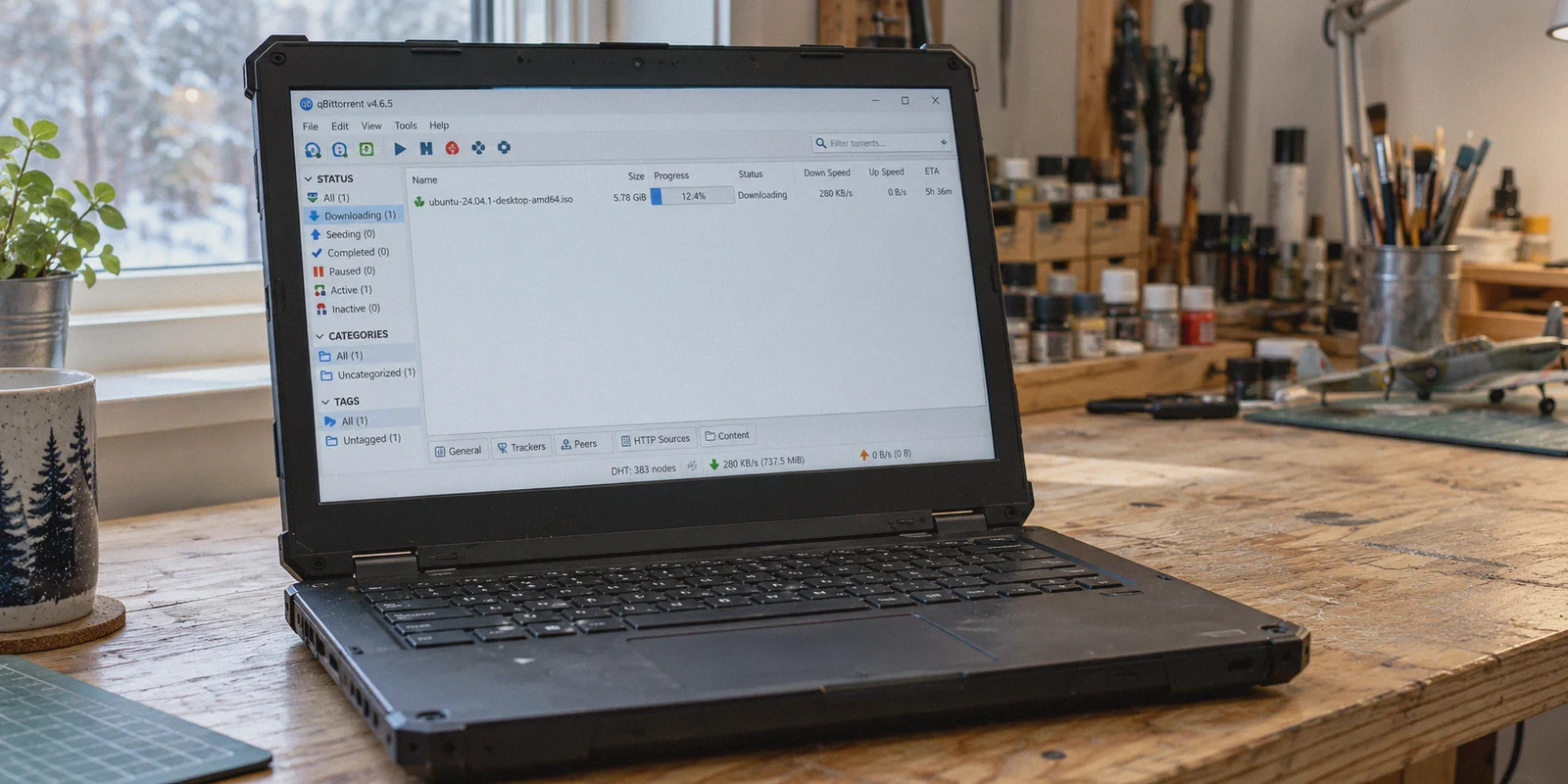 A torrent client downloads a Linux ISO slowly on a laptop.