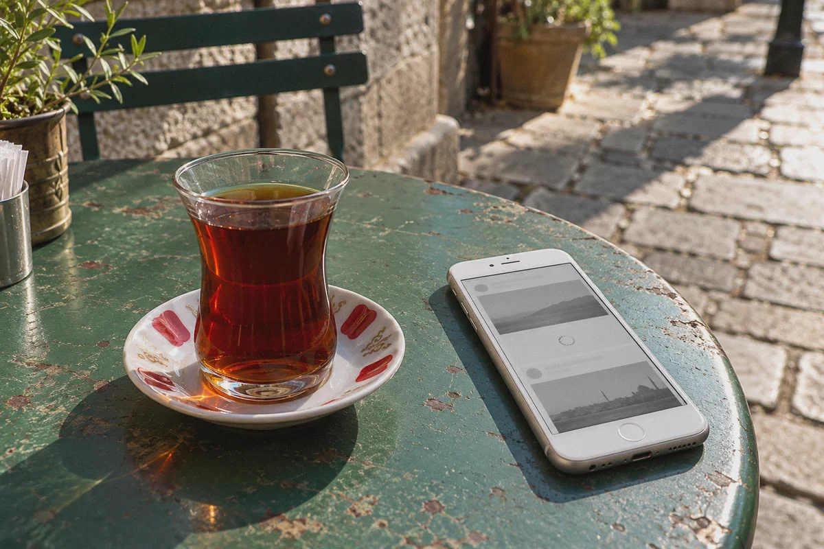 An unfinished social feed loads beside a tea glass at a Turkish cafe.