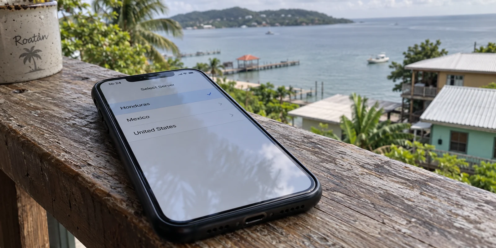 A phone displays Honduras in a server selection list at a Roatán rental.