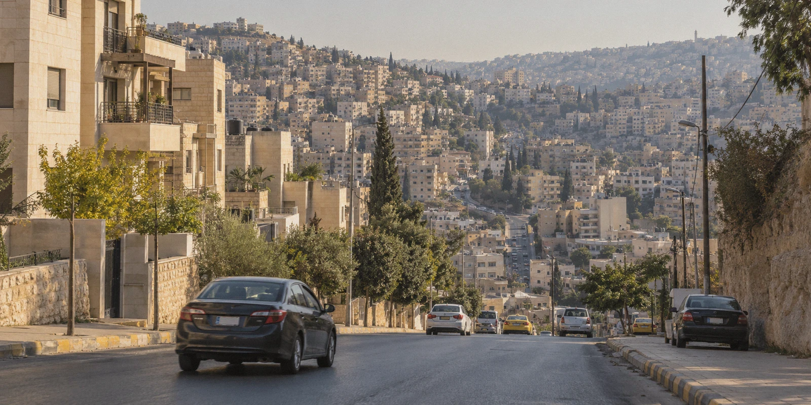 Limestone apartment buildings along a hillside street in Amman.
