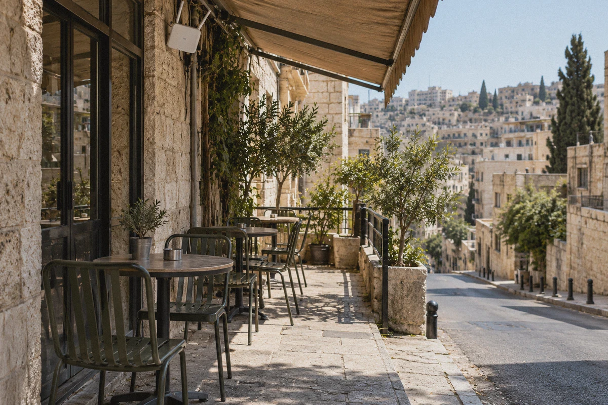 A shaded Amman cafe terrace beside a sunlit street.