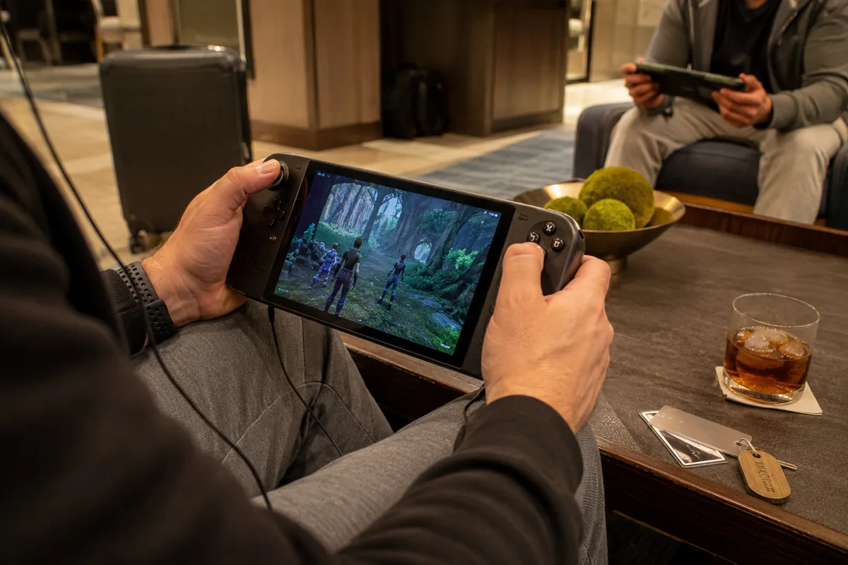 Zwei Reisende spielen in einer Hotellounge gemeinsam auf Handheld-PCs.