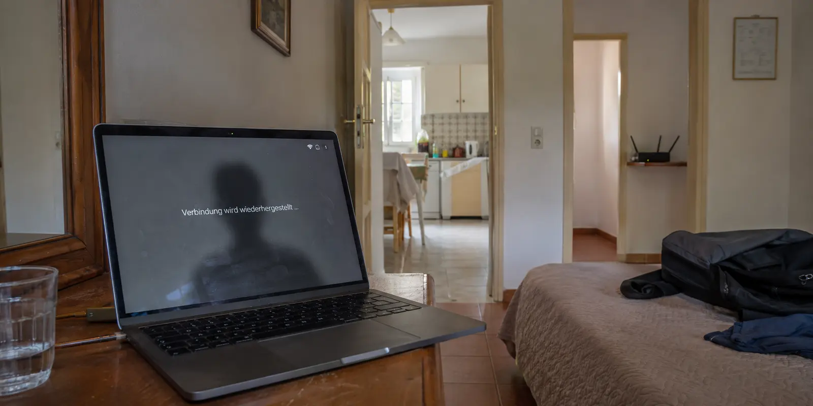 Ein Videocall bricht im Schlafzimmer einer Ferienwohnung ab, während der WLAN-Router mehrere Räume entfernt steht