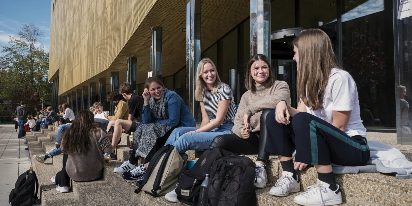 Students with laptops and backpacks outside a university building