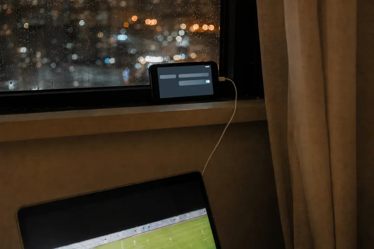 Ein Smartphone stellt am Hotelfenster einen mobilen Hotspot für den weiterlaufenden Fußballstream bereit