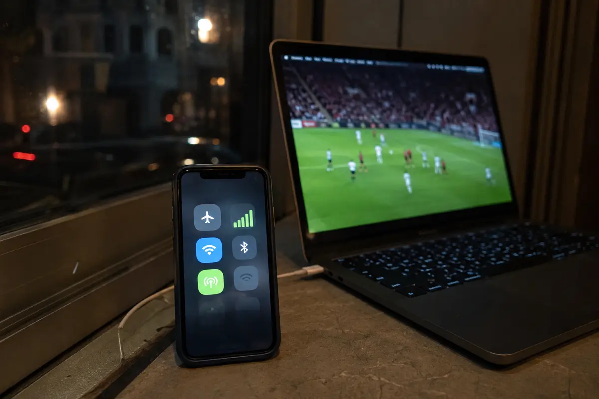 Ein Smartphone hält per Mobilfunk die Verbindung, während der Fußballstream auf dem Laptop wieder läuft