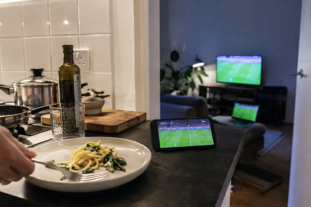 Deutsche Fußballübertragung auf dem Telefon beim Essen in einer Londoner Küche