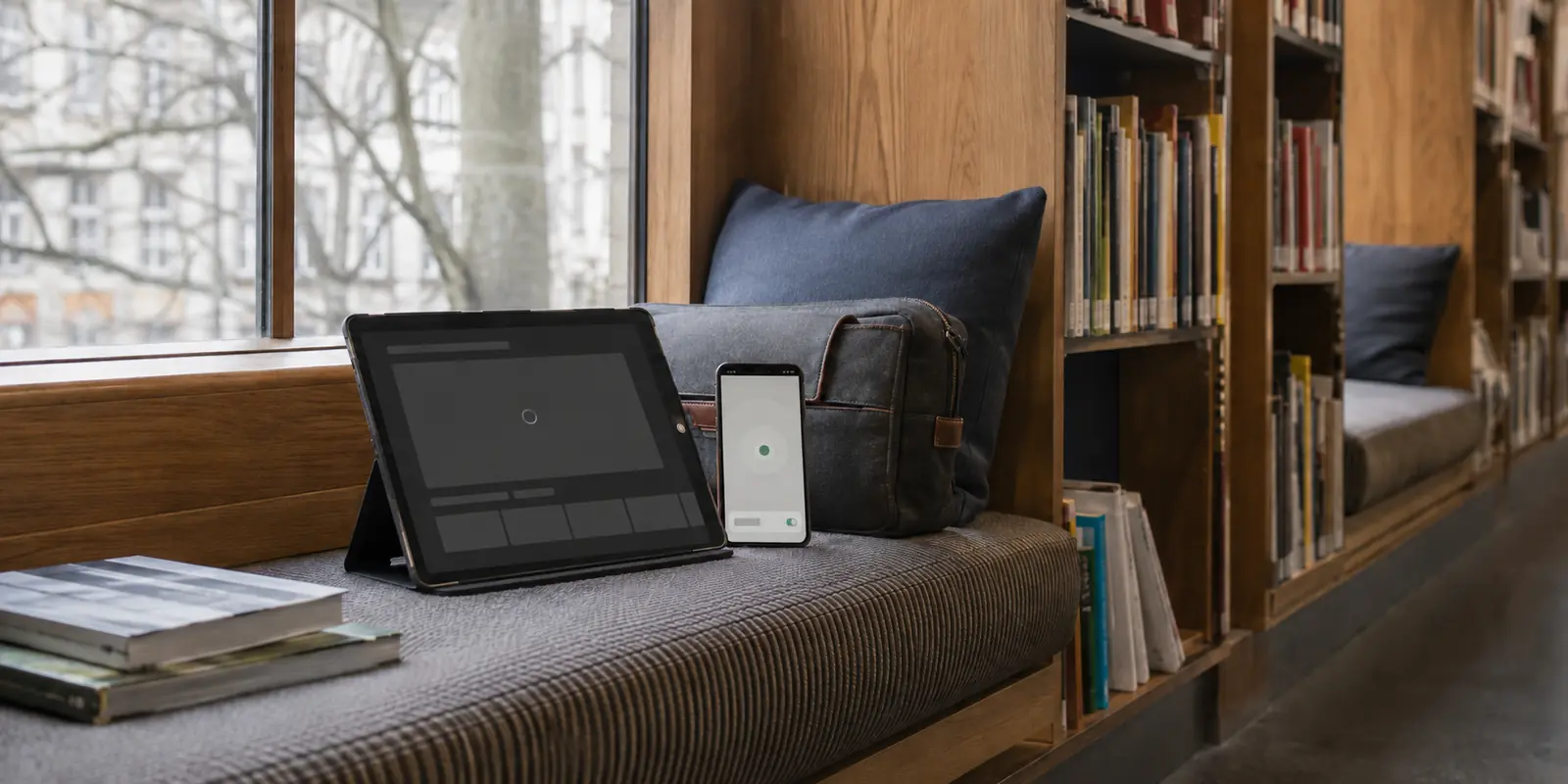 Tablet mit nicht geladenem geschütztem Inhalt neben einem verbundenen Smartphone in einer Bibliotheksnische