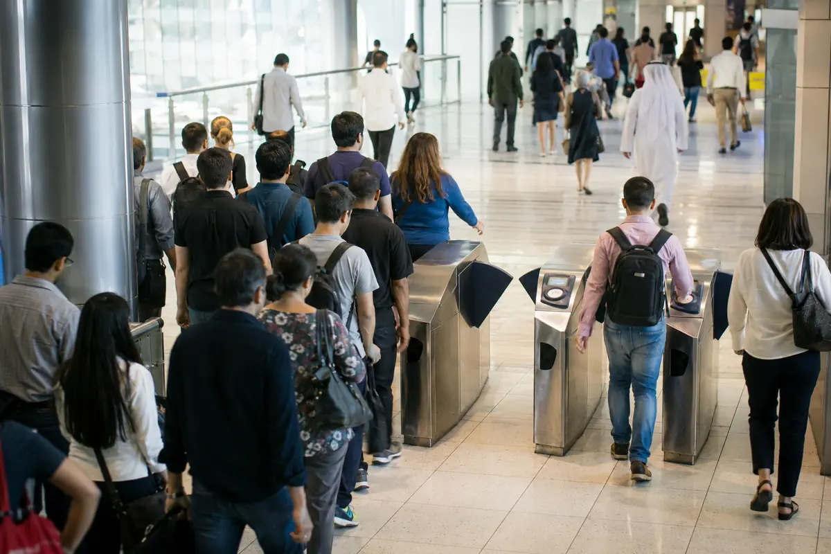 Commuters converging through fare gates in a Dubai Metro concourse