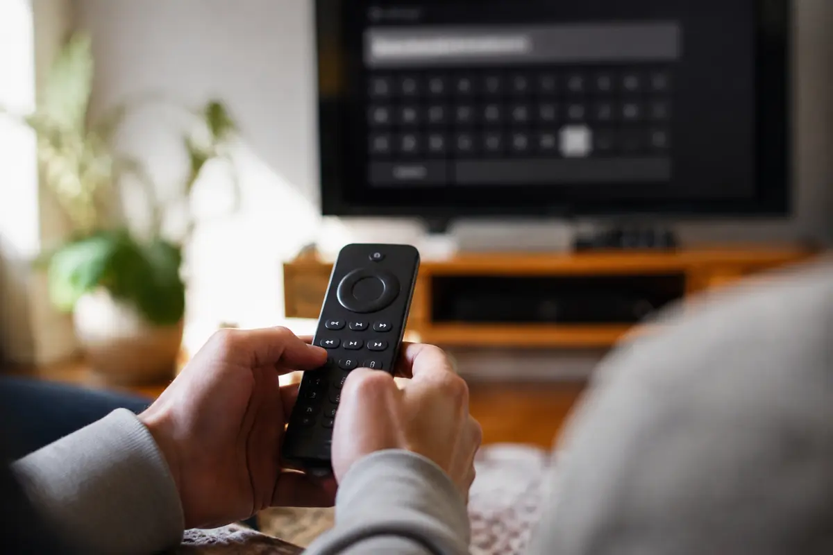 Une personne saisit laborieusement un mot de passe avec une télécommande devant la télévision