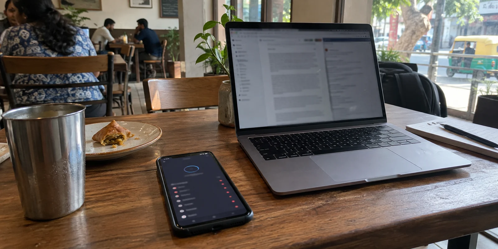 A phone and laptop on a Bengaluru café table while a VPN connection waits for an available route
