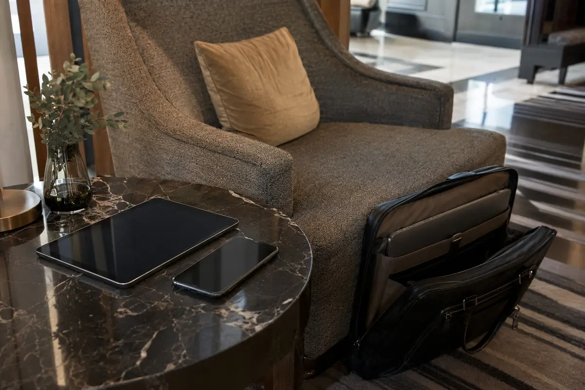 Private Geräte auf einem Hoteltisch und der Firmenlaptop getrennt in einer Arbeitstasche