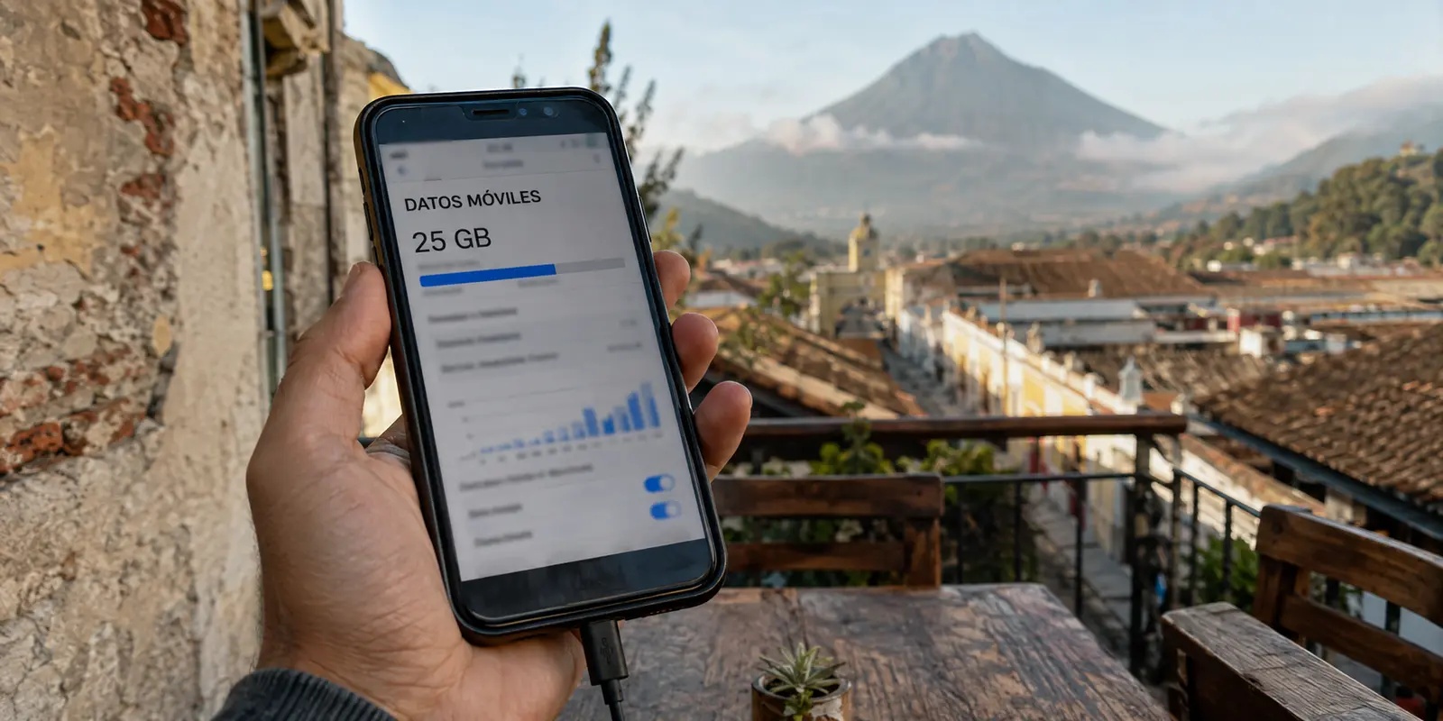 Teléfono mostrando el uso de un paquete de 25 GB frente a los tejados y el volcán de Agua en Antigua Guatemala