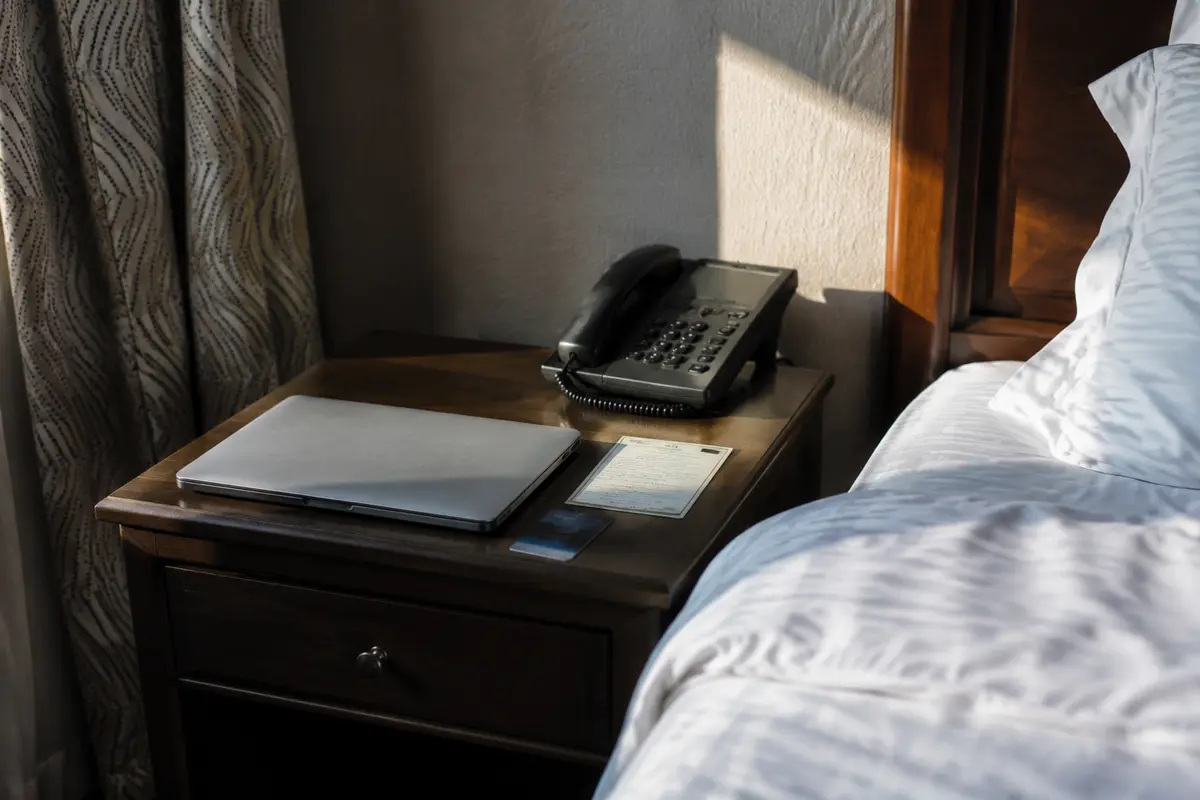 Ordinateur fermé à côté des instructions Wi-Fi et de la carte d’une chambre d’hôtel