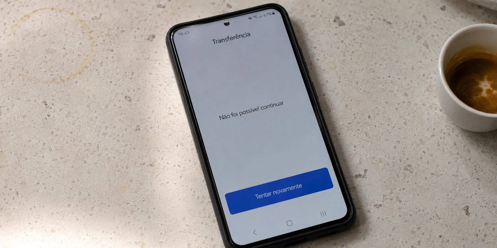 Um celular no balcão de um café mostra uma transferência que não pode continuar.