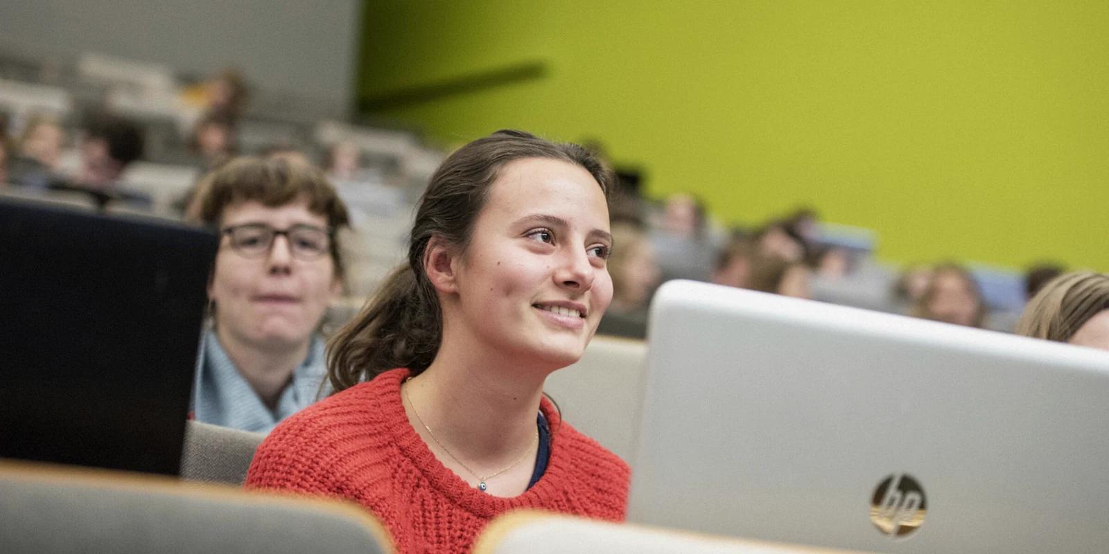 University student working at a laptop in a lecture room.