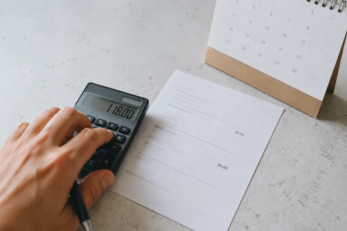 Mano calcula el coste total de una suscripción junto a un calendario y dos importes de pago