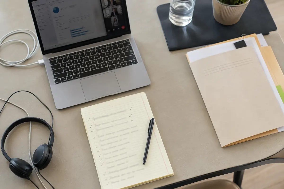Mesa de trabalho com notebook, documentos concluídos e fones após o restabelecimento da conexão