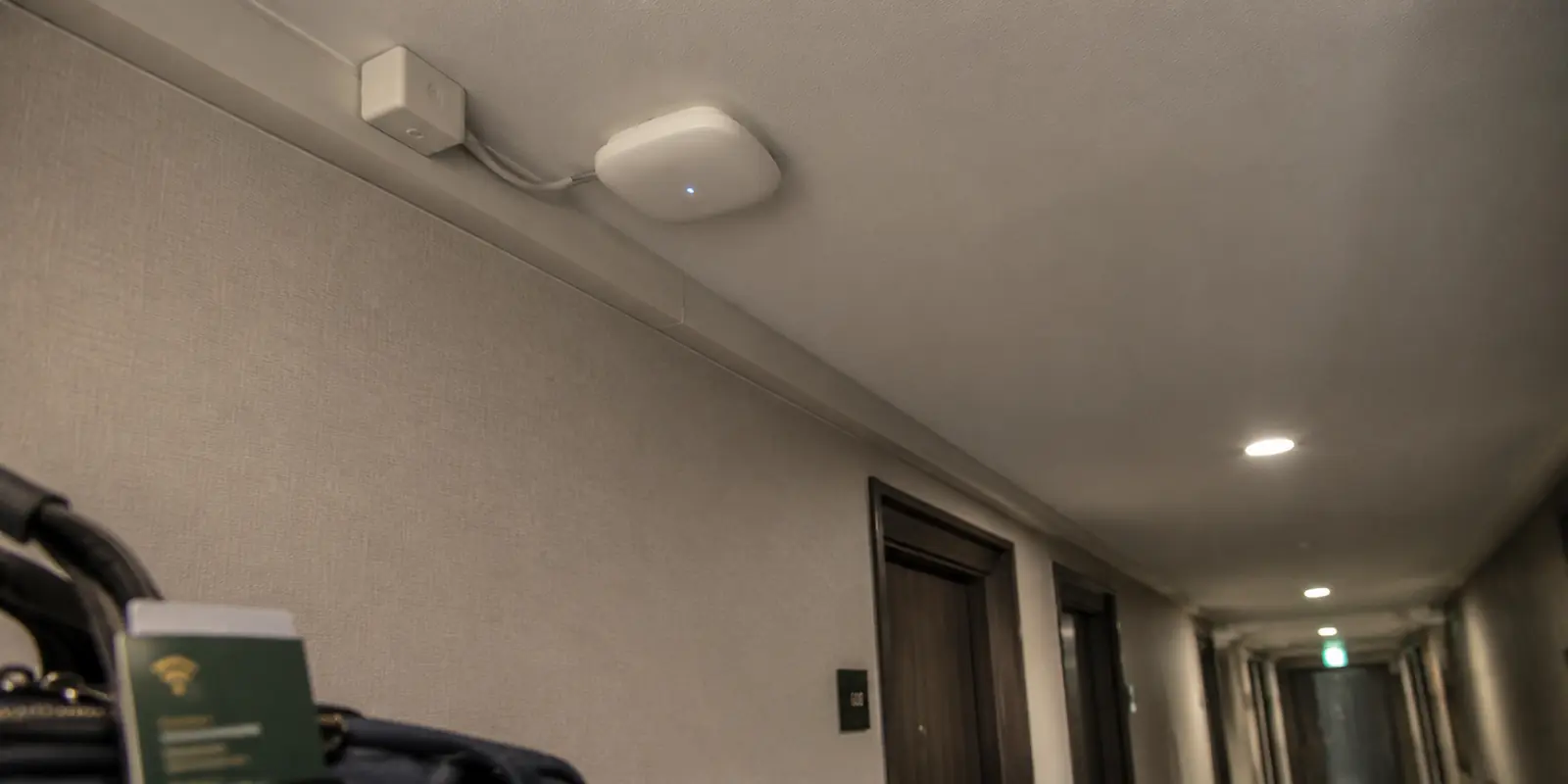 Ponto de acesso Wi-Fi instalado no corredor de um hotel, visto da perspectiva de um hóspede com bagagem