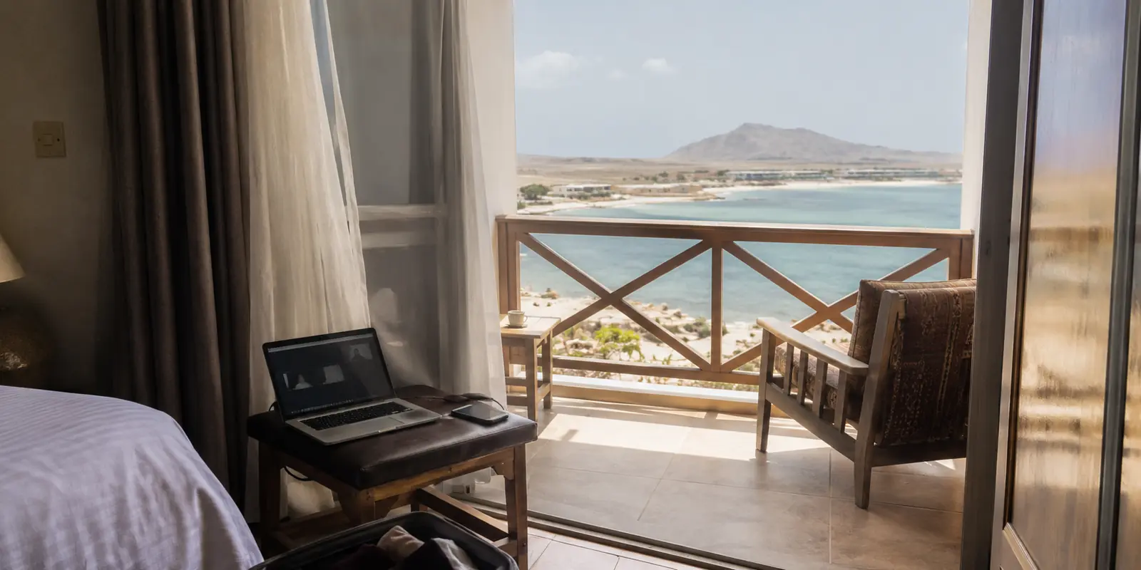 Notebook com chamada interrompida e telefone ao lado em um quarto de hotel com vista para a paisagem de Sal, em Cabo Verde