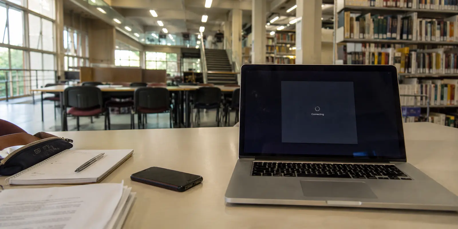 Notebook em uma biblioteca universitária com uma conexão presa na tela de carregamento