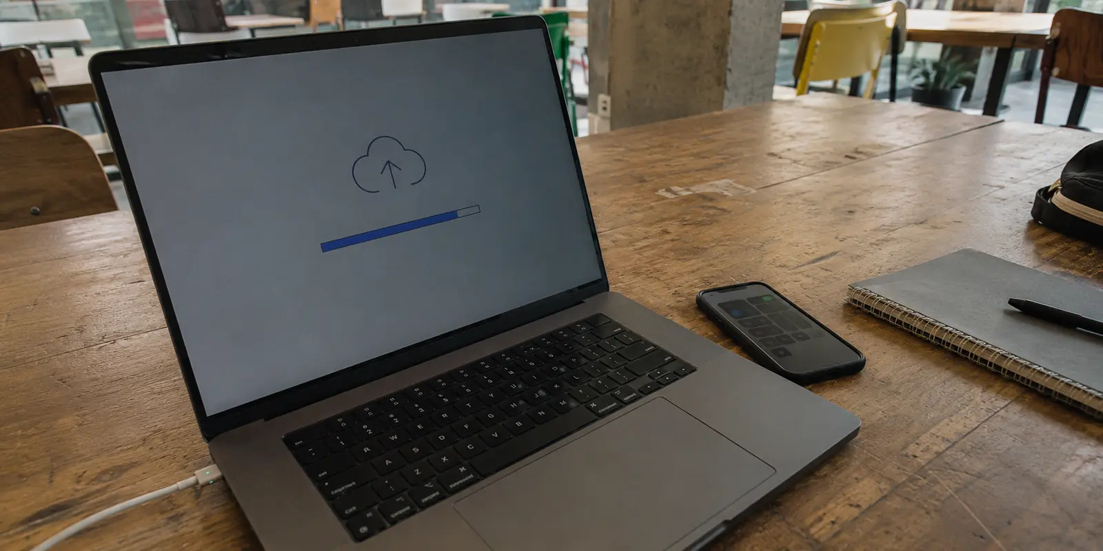 Notebook com um envio quase concluído e interrompido em uma mesa de coworking