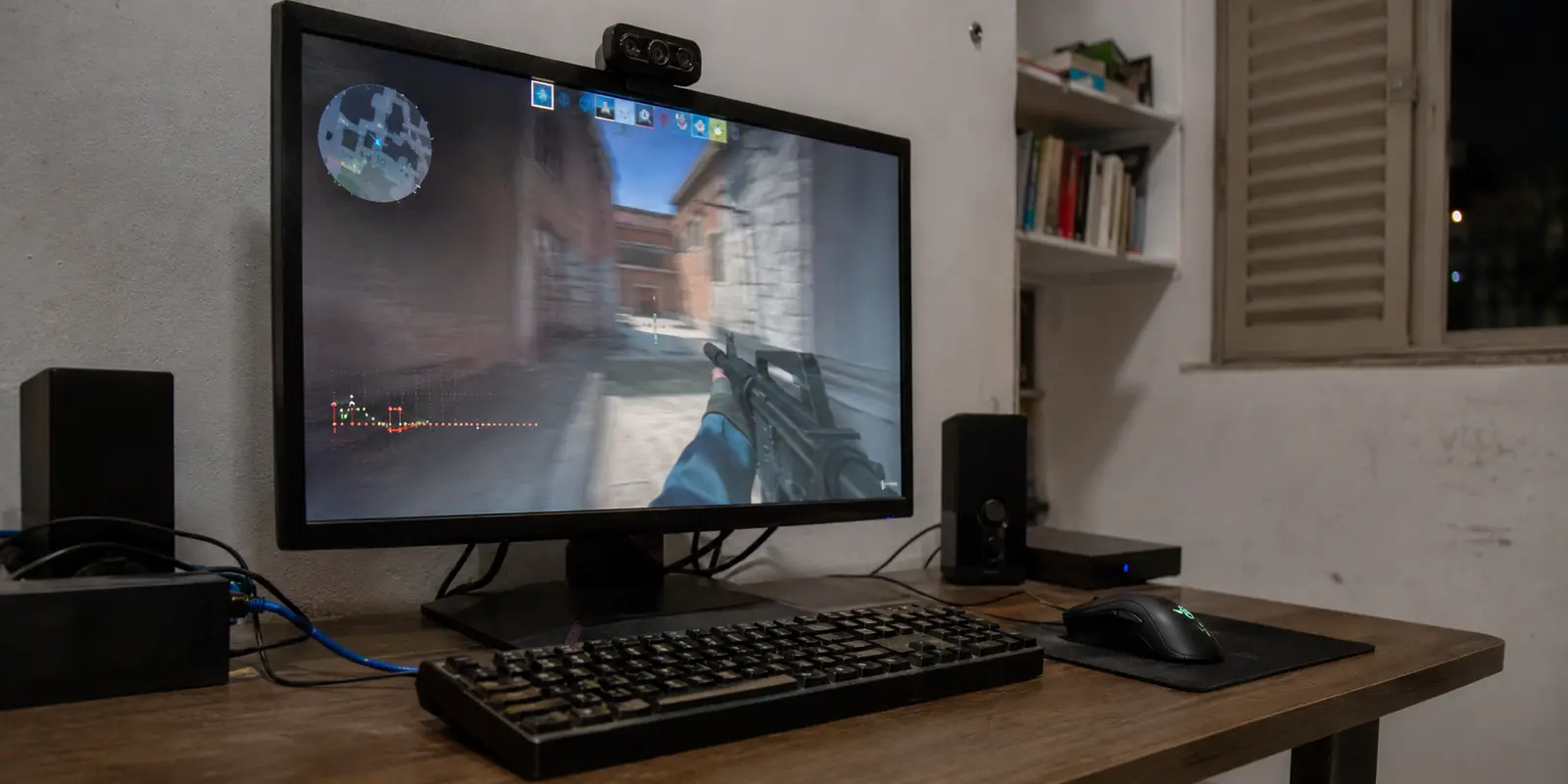 Monitor de um computador conectado por cabo exibindo uma partida com oscilações no gráfico de rede