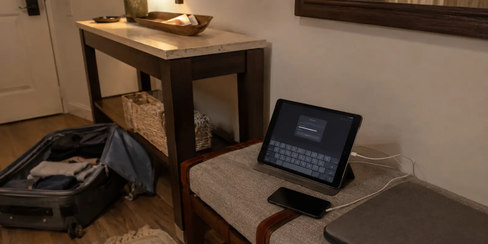 Tablet aguardando autenticação ao lado de um telefone e um portátil fechado numa área de bagagem de uma hospedagem