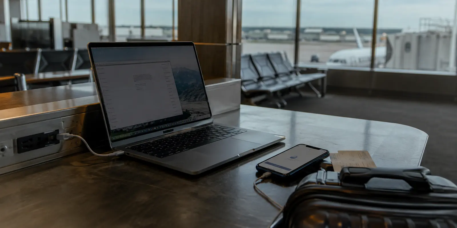 Notebook e celular sobre um balcão de aeroporto antes de uma viagem de negócios