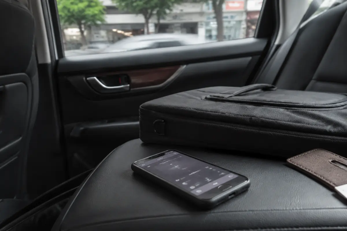 Celular e bolsa de notebook no banco traseiro de um carro durante um deslocamento de trabalho
