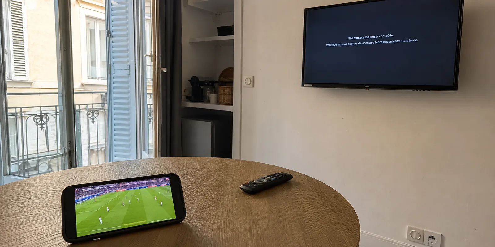 Telemóvel a reproduzir futebol enquanto a televisão mostra uma mensagem de acesso num apartamento em França