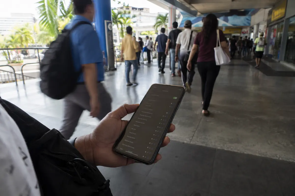 Persona consultando las redes disponibles en su teléfono mientras camina por un paso público concurrido en Ciudad de Panamá