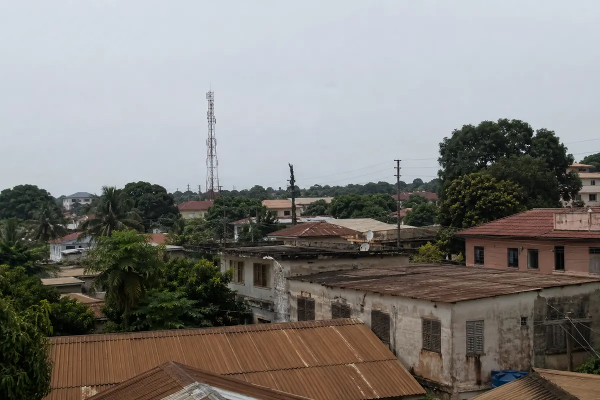 Telhados de Bissau e uma torre de telecomunicações sob o céu úmido