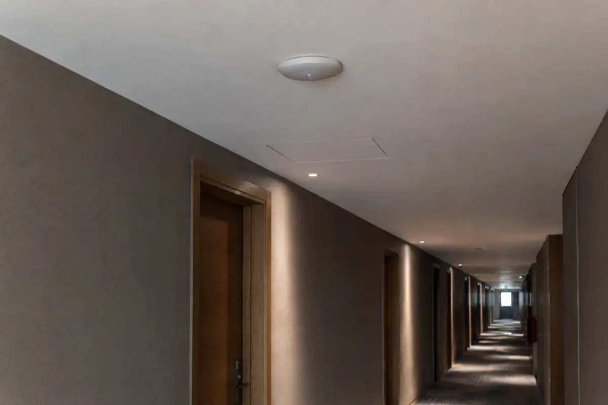 Ponto de acesso Wi-Fi instalado no teto de um corredor com vários quartos de hotel