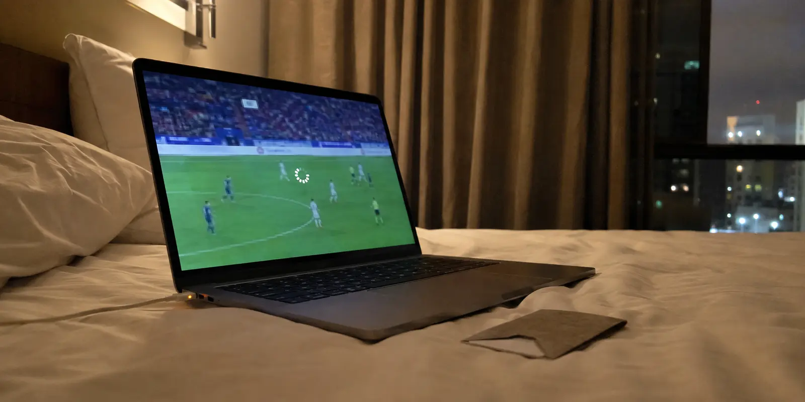 Transmissão de futebol travada em um notebook sobre a cama de um hotel