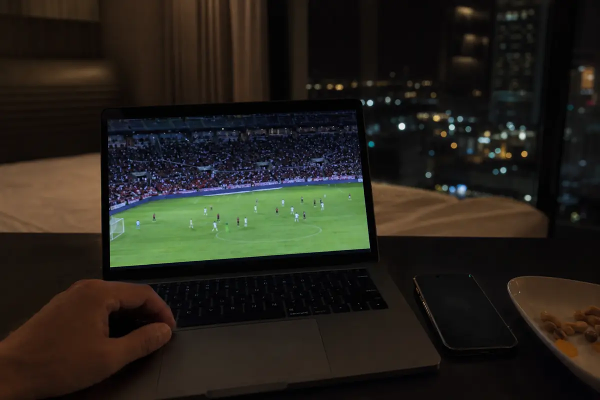 Uma transmissão de futebol decorre num portátil com o telefone ao lado.