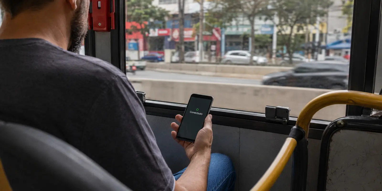 Passageiro em um ônibus urbano de São Paulo com o celular mostrando o status «Conectado».