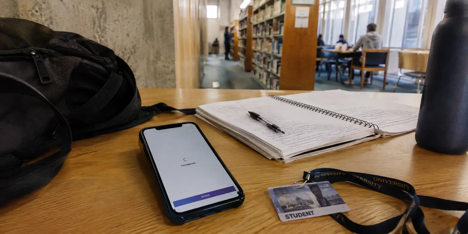 Aplicativo bancário brasileiro preso no carregamento sobre uma mesa de estudos no campus