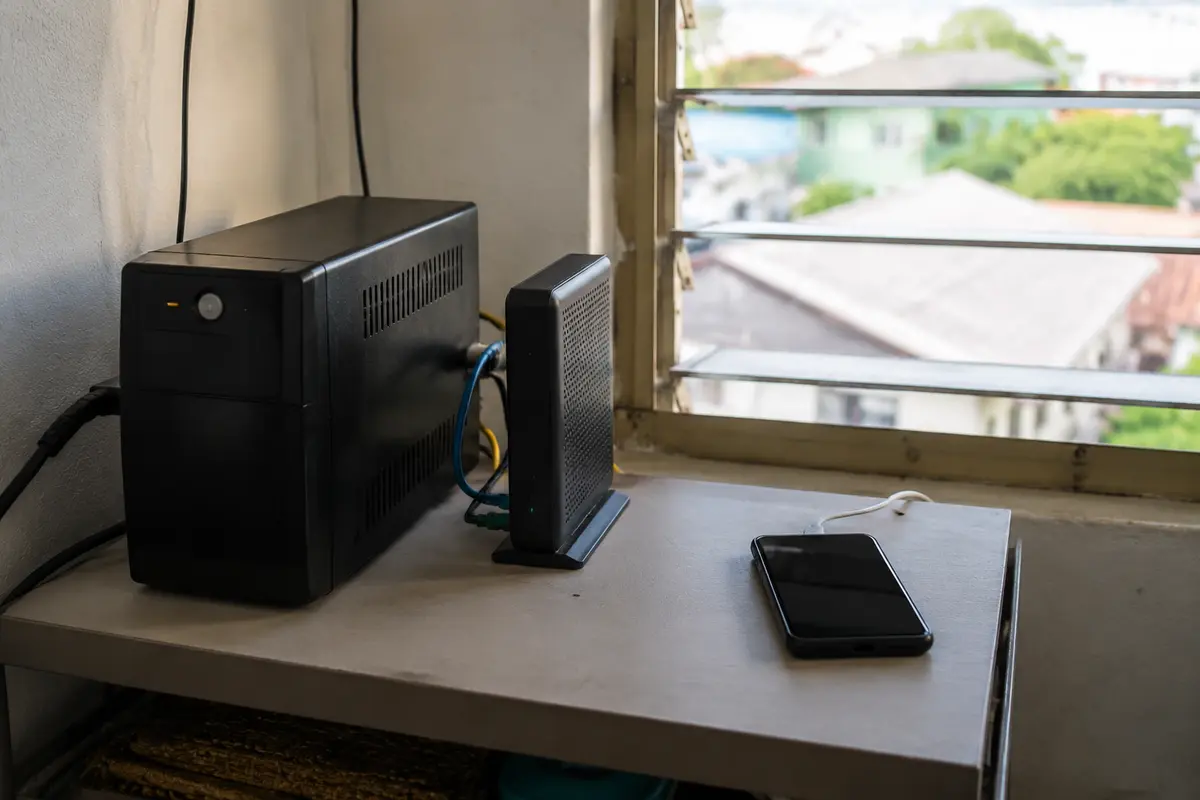 Una batería de respaldo alimenta el equipo de fibra junto a un teléfono preparado como conexión 5G alternativa.