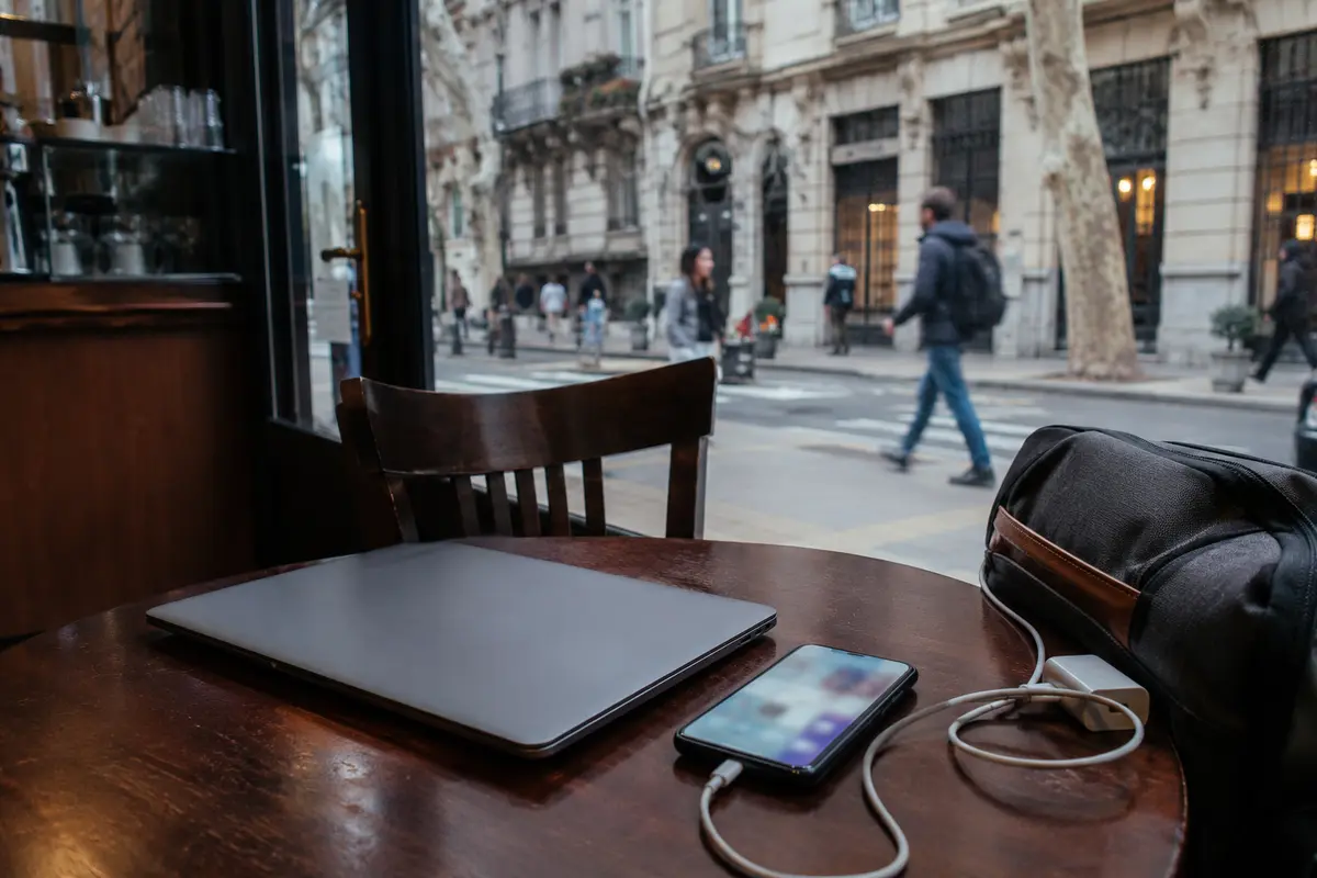 Portátil cerrado, teléfono y mochila sobre una mesa de café en Buenos Aires