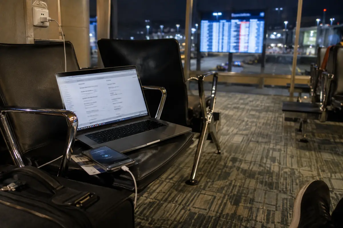 Portátil y teléfono aún conectados durante una espera nocturna por un vuelo reprogramado
