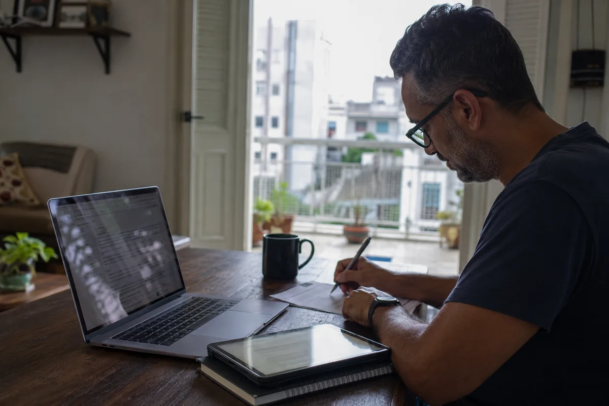 Persona terminando documentos en un portátil y una tableta sin volver a revisar la conexión.