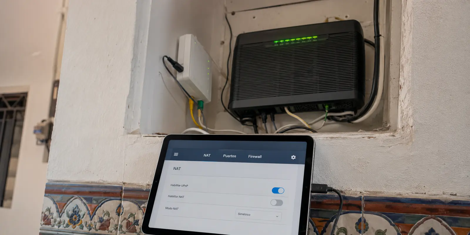 Una tableta muestra los ajustes NAT, puertos y firewall junto al módem de fibra de una casa en México