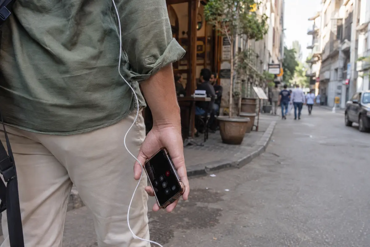 Una persona sigue una conversación de audio mientras se aleja de una cafetería en El Cairo